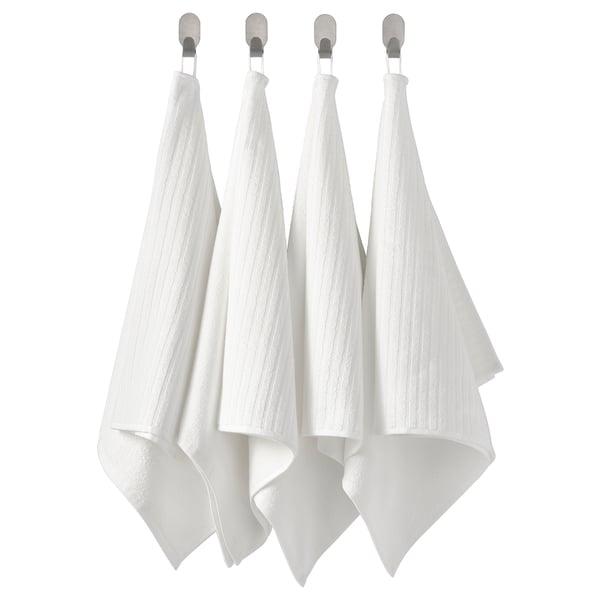 Quatre serviettes blanches pendent soigneusement en rangée à des crochets. Alternative : quatre serviettes blanches soignées sont suspendues à des crochets en argent.