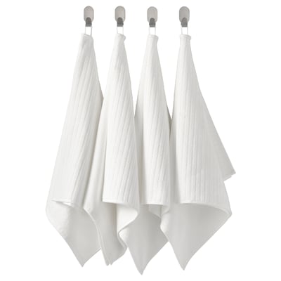 Quatre serviettes blanches pendent soigneusement en rangée à des crochets. Alternative : quatre serviettes blanches soignées sont suspendues à des crochets en argent.