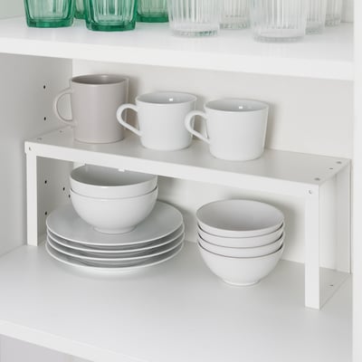 L’organisateur à étagères blanches empile les tasses, les bols et les assiettes dans l’armoire pour un rangement efficace.