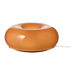 Une lampe en verre orange VARMBLIXT en forme de beignet, dotée d’une lueur chaleureuse et d’un design élégant.