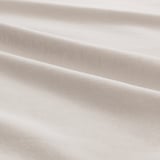 Gros plan sur un tissu en jersey de coton beige doux, mettant en valeur sa texture lisse et son tissage fin.