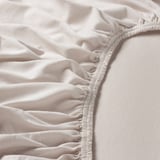 Gros plan d’un drap en jersey de coton blanc doux avec un liseré élastique, mettant en valeur sa texture lisse et sa qualité de fabrication.