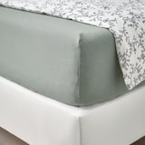 Lit avec draps en jersey VÅRVIAL vert clair et surmatelas imprimé floral, mettant en valeur un coin aménagé.