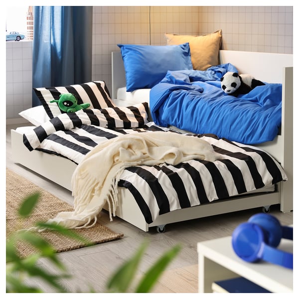 Chambre confortable avec lit de repos à rayures blanches et noires, draps bleus et animaux en peluche.