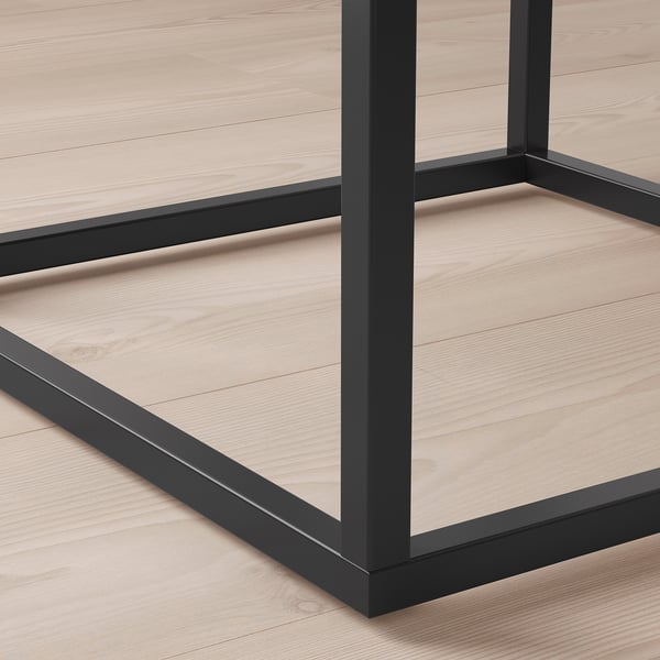 Gros plan de tables modernes robustes, pieds en métal noir et surface en bois clair, présentant un design élégant et des matériaux de qualité.