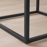 Gros plan de tables modernes robustes, pieds en métal noir et surface en bois clair, présentant un design élégant et des matériaux de qualité.