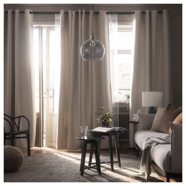 Une chambre moderne avec des rideaux gris, une table ronde, un lit, une grande fenêtre et une lumière globe.