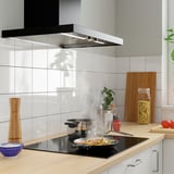 Cuisine moderne avec cuisinière à induction, légumes colorés, comptoir en bois et dosseret gris.