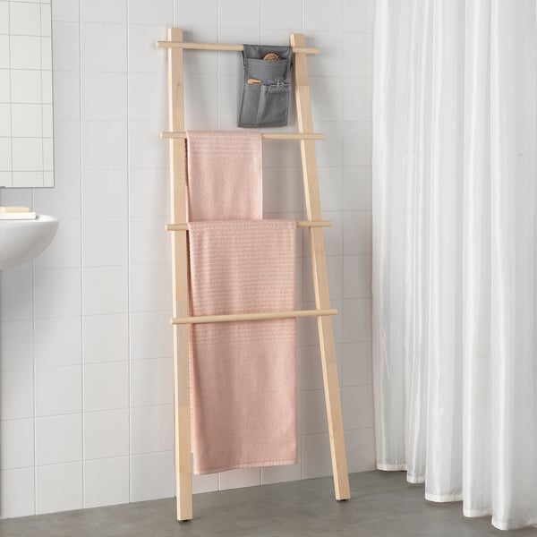 Porte-serviettes en bois avec serviettes roses et trousse de toilette dans le coin de la salle de bain.