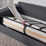 La personne tire un canapé-lit avec un matelas épais. Facile à convertir et confortable pour dormir.