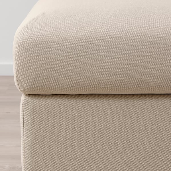 Gros plan sur les repose-pieds VIMLE en tissu moelleux beige. Texture douce, design épuré.