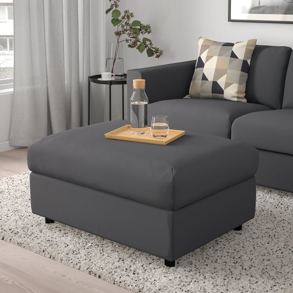 Salon moderne avec sectionnel VIMLE, pouf, coussins et grande fenêtre.