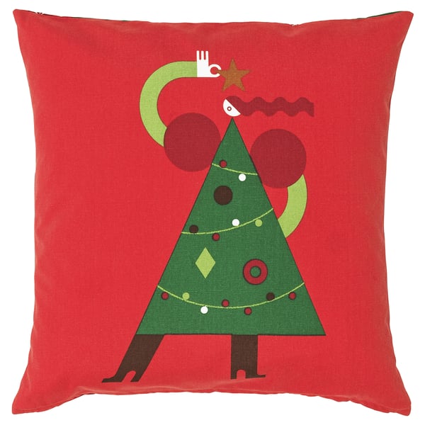 Coussin carré rouge avec motif d’arbre de Noël vert ; visage blanc, ornements bruns, décorations colorées.
