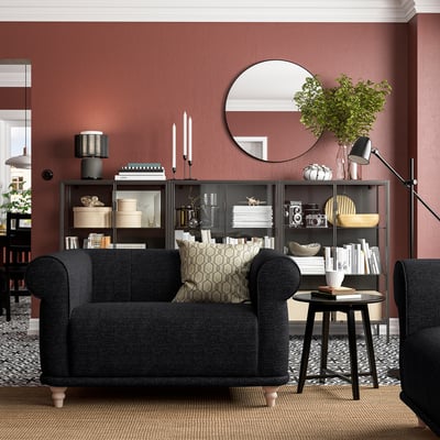 Fauteuil VISKAFORS gris foncé, miroir rond, étagère, mur rouge, aménagement confortable du salon.
