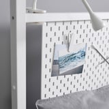 Panneau perforé blanc avec des pinces contenant des photos et des notes, fixé à un cadre en métal robuste, mettant en valeur l’organisation et la fonctionnalité.