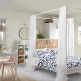 Chambre moderne avec lit à baldaquin VITARNA, literie bleue, panneau perforé et coin repas.