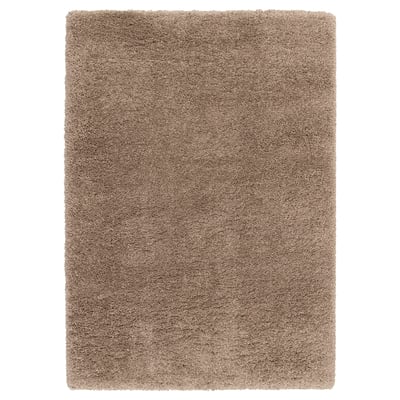 Un tapis beige hirsute VOLLERSLEV avec différentes épaisseurs de fils, offrant une texture douce et des propriétés insonorisantes.