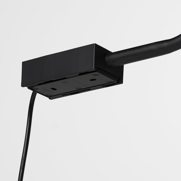 Fixation de lampe noire avec bras robuste et flexible, conçue pour des réglages précis de l’éclairage, fixée sur une surface métallique.