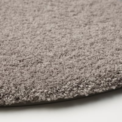 Round, grey, plush bath mat with soft microfiber texture, recycled polyester pile, and latex backing, ideal for comfort and absorption.