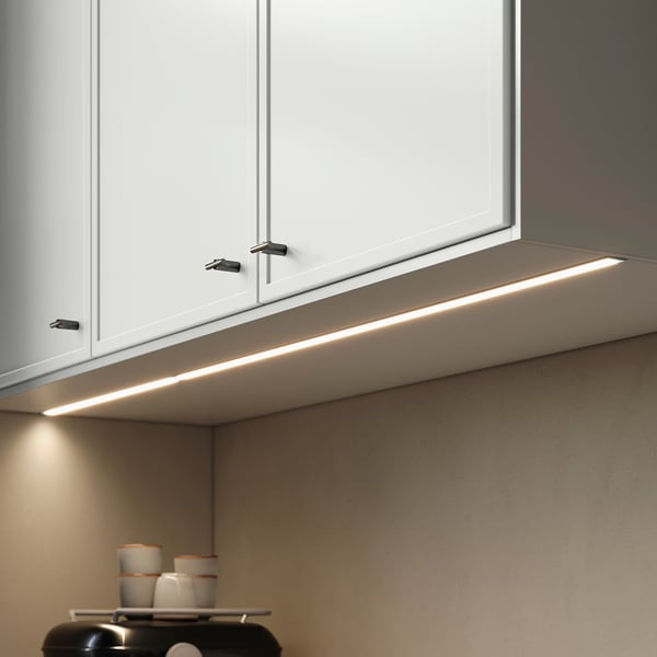 Under-cabinet lighting strip, sleek grey, modern design, attaches below white kitchen cabinets.