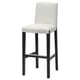 A white upholstered bar stool named BERGMUND with black wooden legs. It has a high back for support and a footrest for comfort.