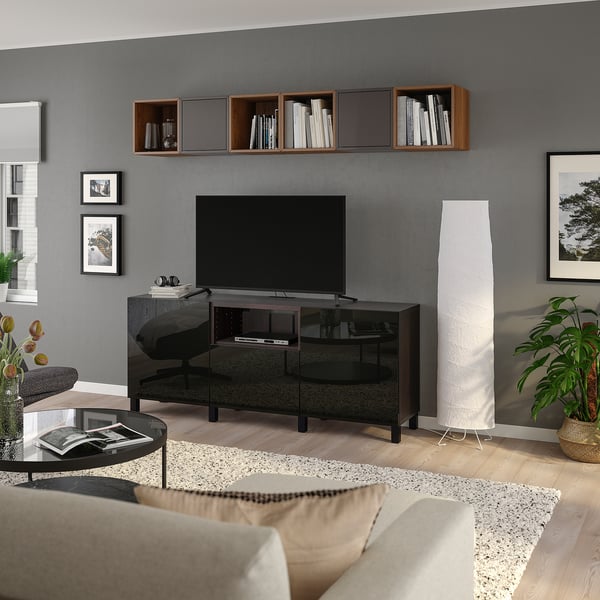 Modern living room with grey walls, flat-screen tv, shelves, sofa, and plants.