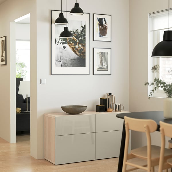 Minimalist dining area with BESTÅ sideboard in light beige, bowl, plants, photos, & pendants.