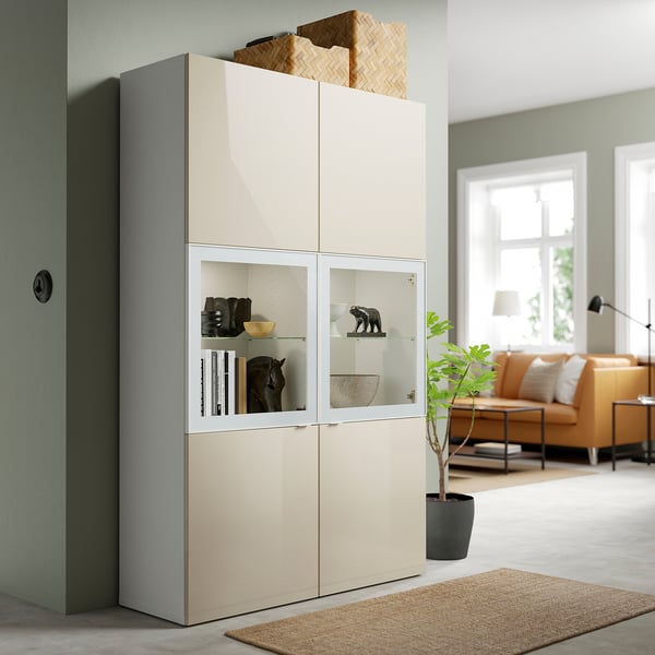 Beige BESTÅ unit with grey accents, tall, mixed shelves & glass doors.