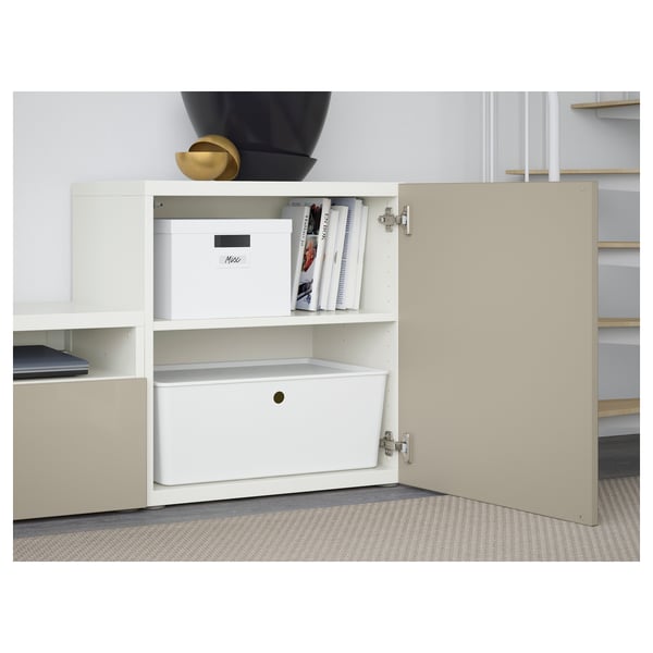 Open white BESTÅ cabinet showing adjustable shelves with storage boxes, books, and drawers.