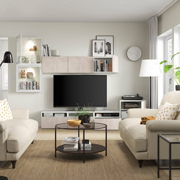 Modern living room with white couches, flat-screen tv, and storage units featuring adjustable shelves, push-open drawers, and cable management.