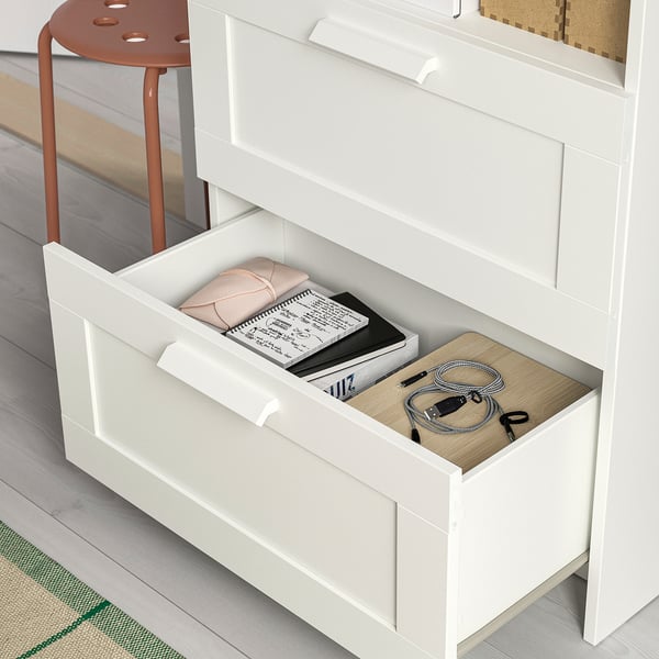 Open white drawer with books, cables, and cloth; part of a multi-piece furniture set.