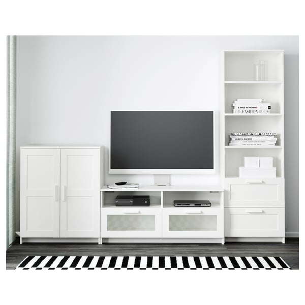 Modern living area with white furniture: tv on stand, storage drawers, adjustable shelves, and cable management. Black and white striped rug.