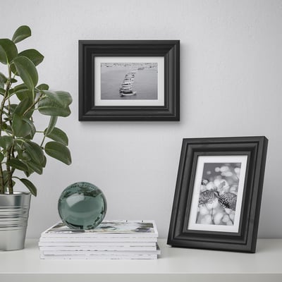 Decorative shelf with framed photos, plant, and glass sphere.