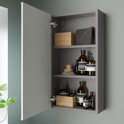 Open grey wall cabinet reveals organised bathroom items: bottles, boxes, and brushes. Easy access and space-saving.