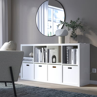 KALLAX shelf with books, mirror, chair, plant, lamp.