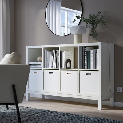 White KALLAX shelf with books & decor near sofa, visible base
