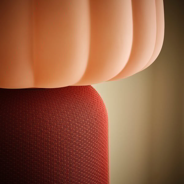 A peach-colored KULGLASS lamp with a textured red fabric cover and a rounded, ribbed glass shade.