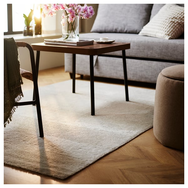 Cosy living room with grey sofa, wooden coffee table, and cream rug.