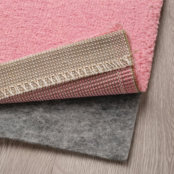 Pink, textured rug layers on wooden floor, showing soft feel and cosy design.