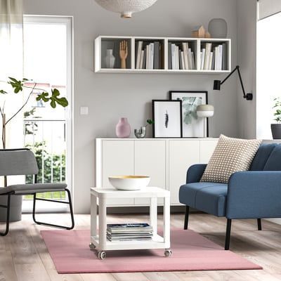 Living room with LANDSVÄG rug, blue couch, white furniture, bookshelf, lamp.