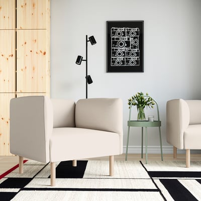 Modern living room with two beige LILLEHEM sofas around a green table, vase of flowers, black & white camera poster, and geometric rug.