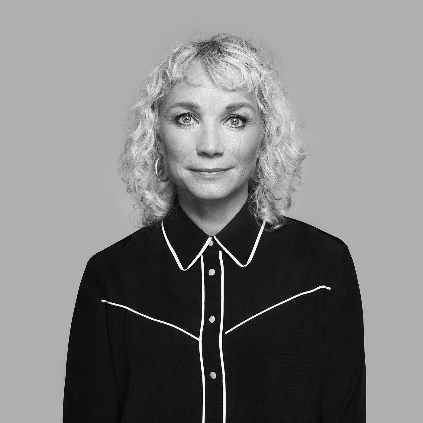 Black and white portrait of Maria Vinka with curly hair, wearing a black blouse with white trim.