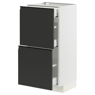Displays a modern white METOD kitchen cabinet with black matte upplöv drawer fronts, featuring sleek, integrated handles and a minimalist design.