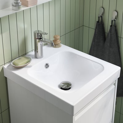 A white ORRSJÖN wash-basin. Square-shaped with smooth edges. It has a single drain hole. Attached is a white plumbing setup.