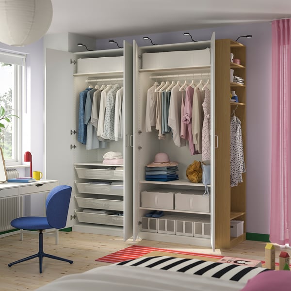 Modern kids bedroom featuring a PAX wardrobe with hanging clothes, shelves, and storage drawers. Includes a desk, chair, and a colourful rug.