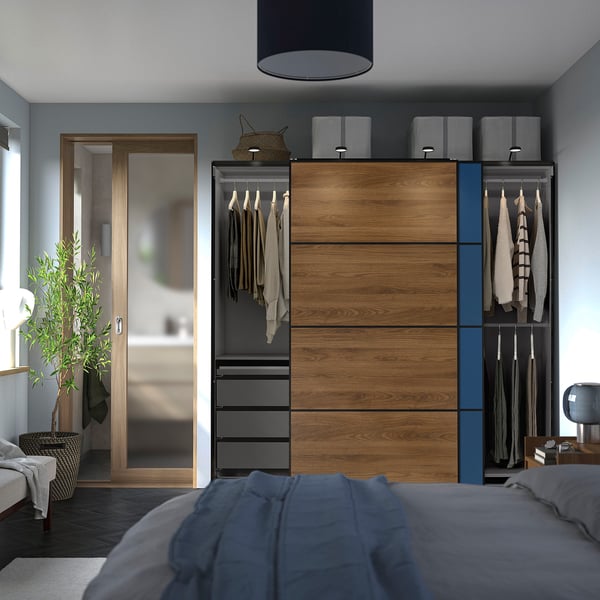 Modern bedroom featuring a large PAX wardrobe with sliding doors, hanging clothes, and multiple storage compartments.