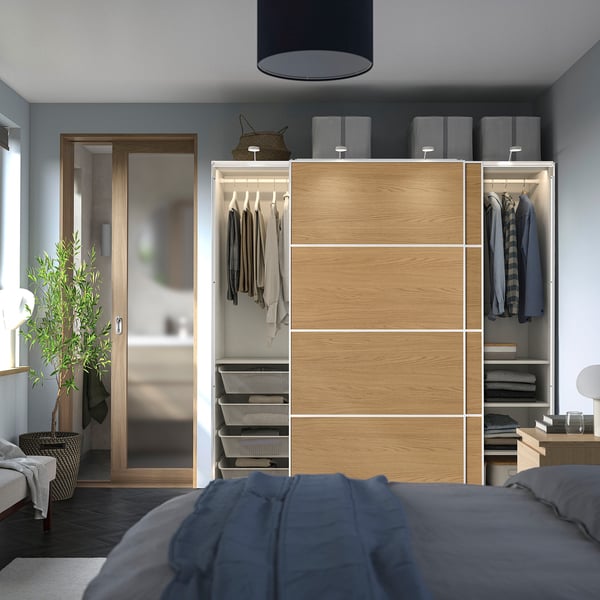 Bedroom with a PAX wardrobe featuring sliding doors, hanging clothes, shelving, and organised drawers.