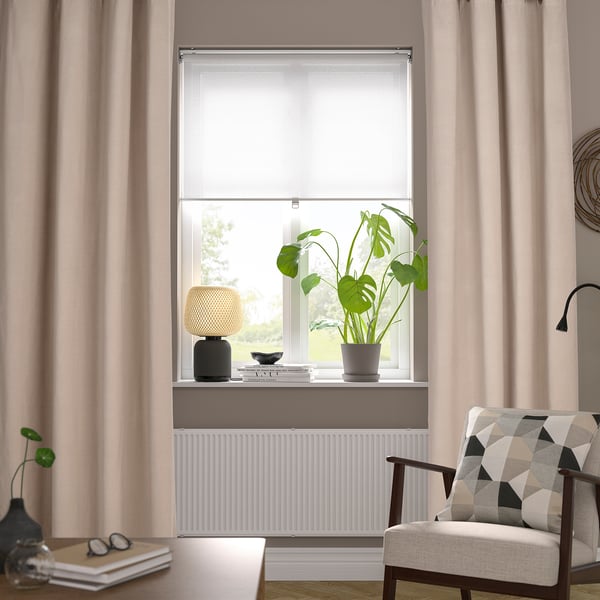 Living room with beige curtains, wooden chair, and plant-lit windowsill.