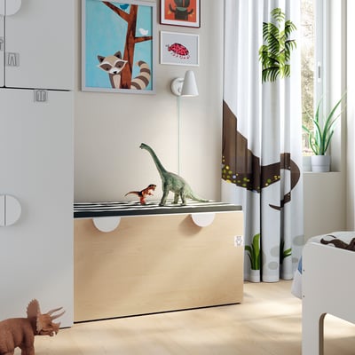 Kids room with SMÅSTAD toy bench, white. Dinosaur toys, art prints, light wood floor, plants.