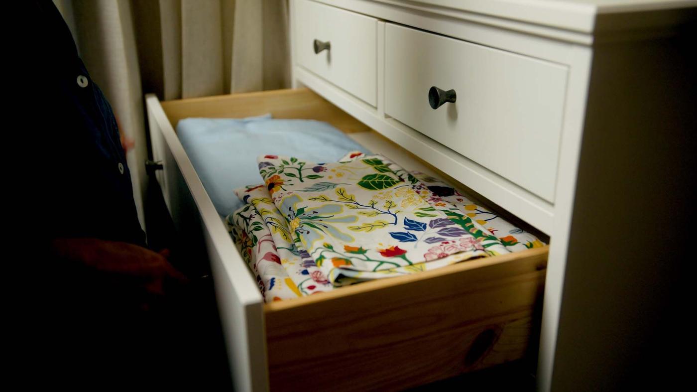 An open chest of drawers revealing neatly folded floral fabric.